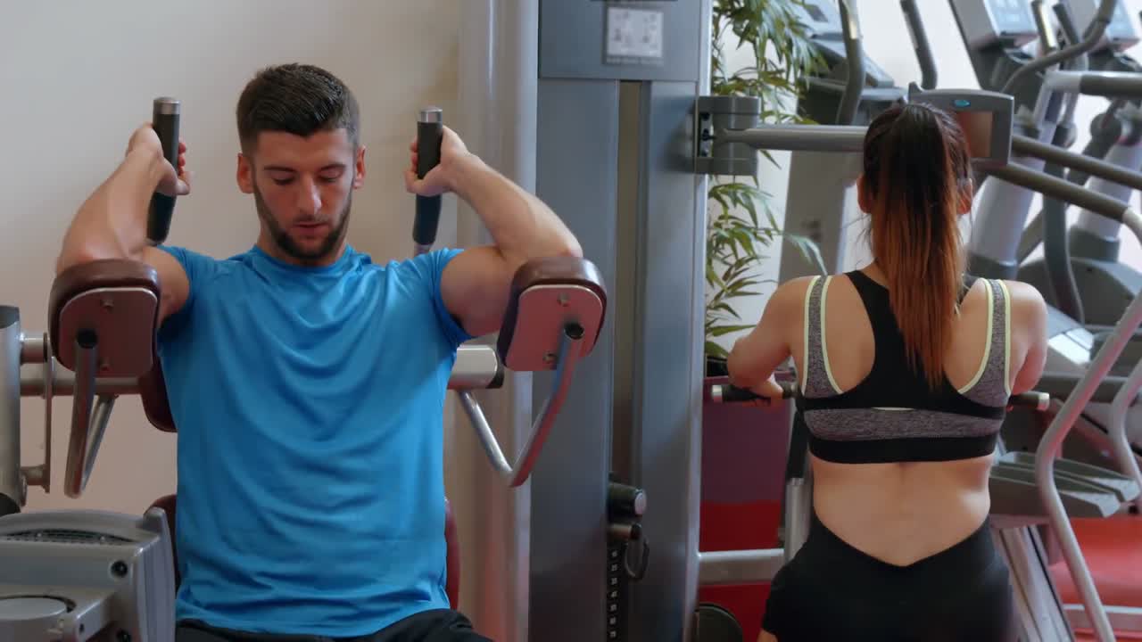pareja usando una máquina de pesas en el gimnasio
