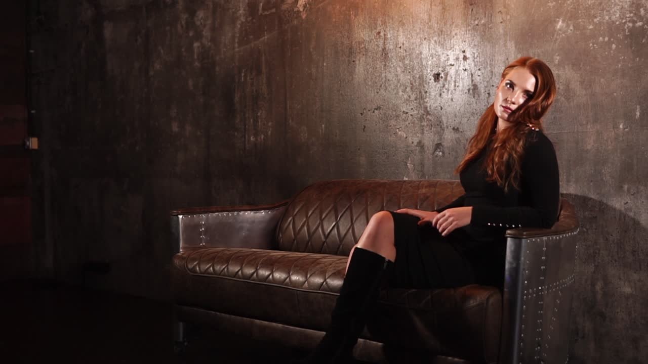 가죽 소파 에 검은 드레스 를 입은 여자