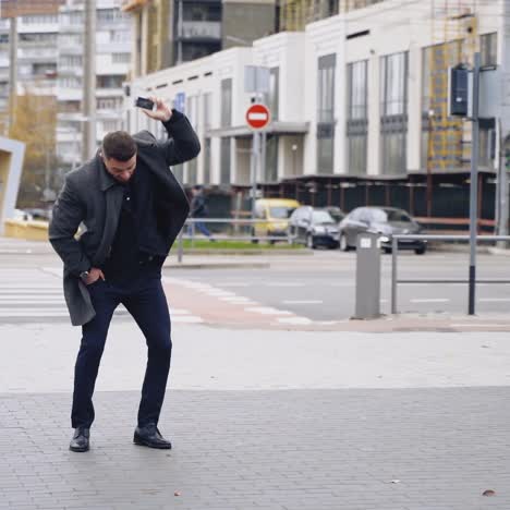 portrait of a handsome young businessman dressed in formal clothes. male in coat crosses the road and using mobile phone