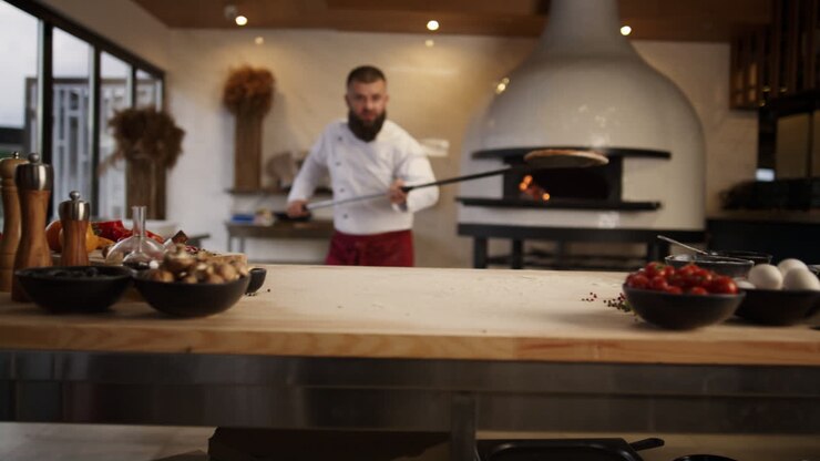 Chef che cucina pizza italiana in una cucina professionale di ristorante.