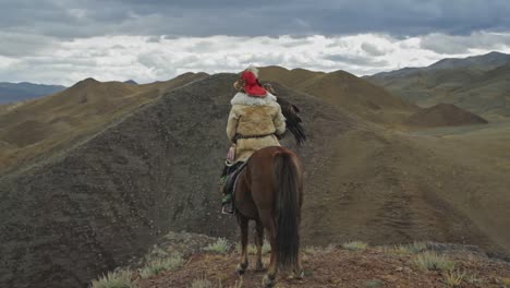 cazador de águila dorada de kazajistán a caballo con vistas a las cimas de las montañas altai, mongolia