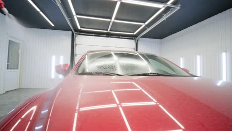 car washing cleaning with foam and high pressured water. red car