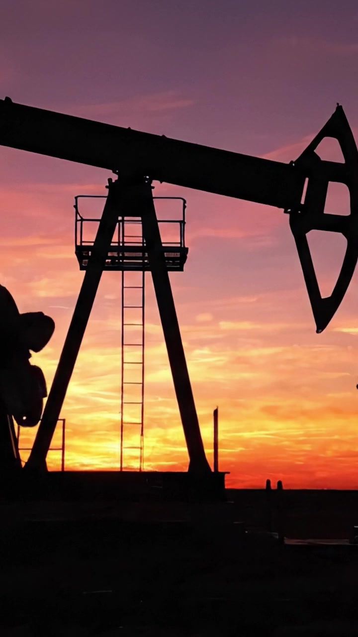 Silhouetted Oil Pump Jack Against a Vibrant Sunset Sky: A Striking Display of the Energy Industry's Machinery and Natural Beauty at Dusk