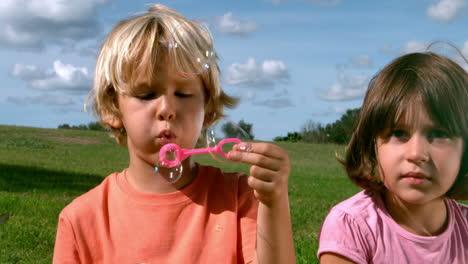 small boy blowing bubbles with a girl