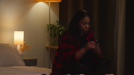 woman checking phone in bedroom at night