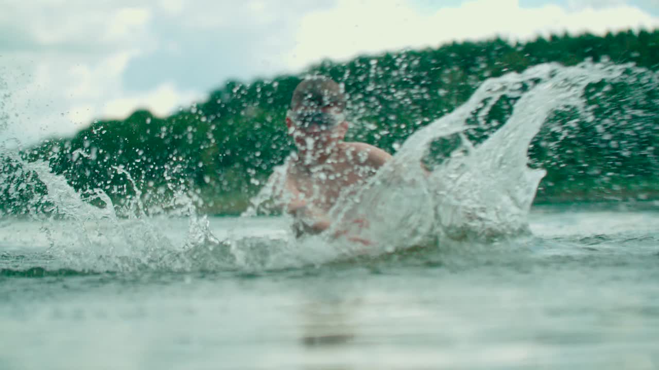 즐거운 백인 아이가 호수에 물을 뿌린다