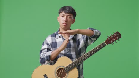 adolescente asiático con guitarra haciendo un gesto de tiempo con las manos en el fondo de la pantalla verde