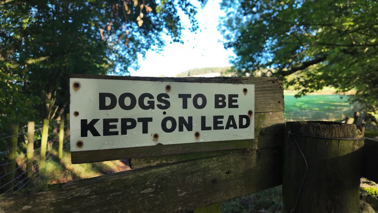 Rustic farm fence with a warning sign reminding visitors dogs must be kept on a lead