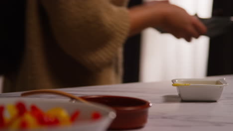 close up of woman at home in kitchen preparing healthy vegetarian or vegan meal eating bowl of salad leaves with seeds and dressing 3