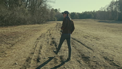 young photographer walks through an open field in the sunshine