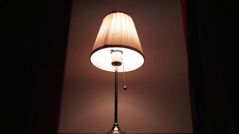 close up shot of white table lamp being turned on with a male hand