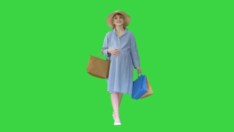 pregnant woman in summer clothes walking with shopping bags on a green screen, chroma key