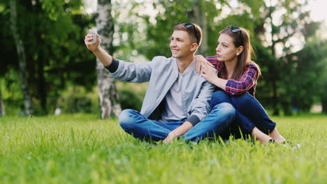 young couple resting in a park makes selfie hd video