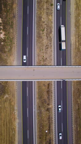 aerial top down view of farm bridge over highway crossroads in summer - vertical video