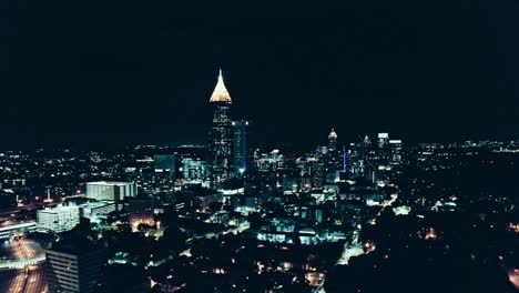 skyline of atlanta lighting at night. american town with bank of america plaza, usa. aerial drone wide shot. futuristic concept with blue colored lights.traffic on highway in metropolis. panorama view