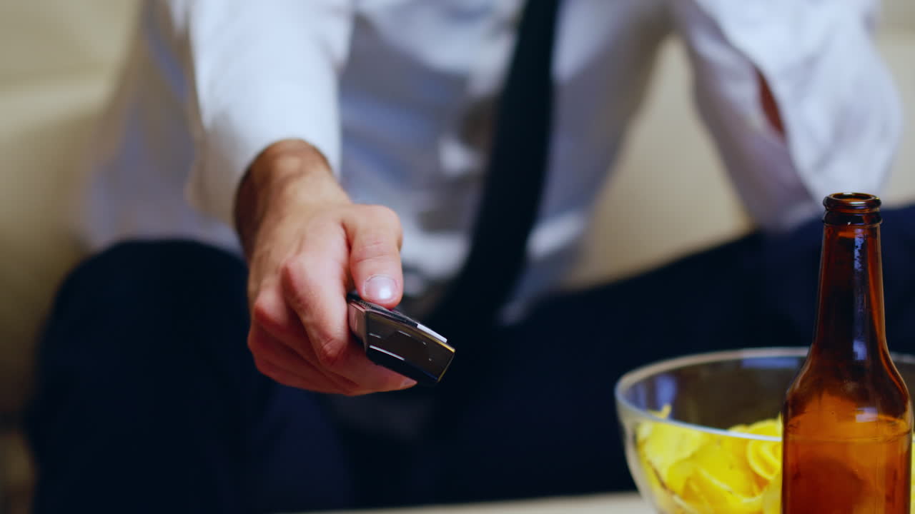 Close up of businessman sitting on couch using remote control