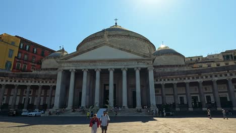 tourists walk by historic architecture and statue