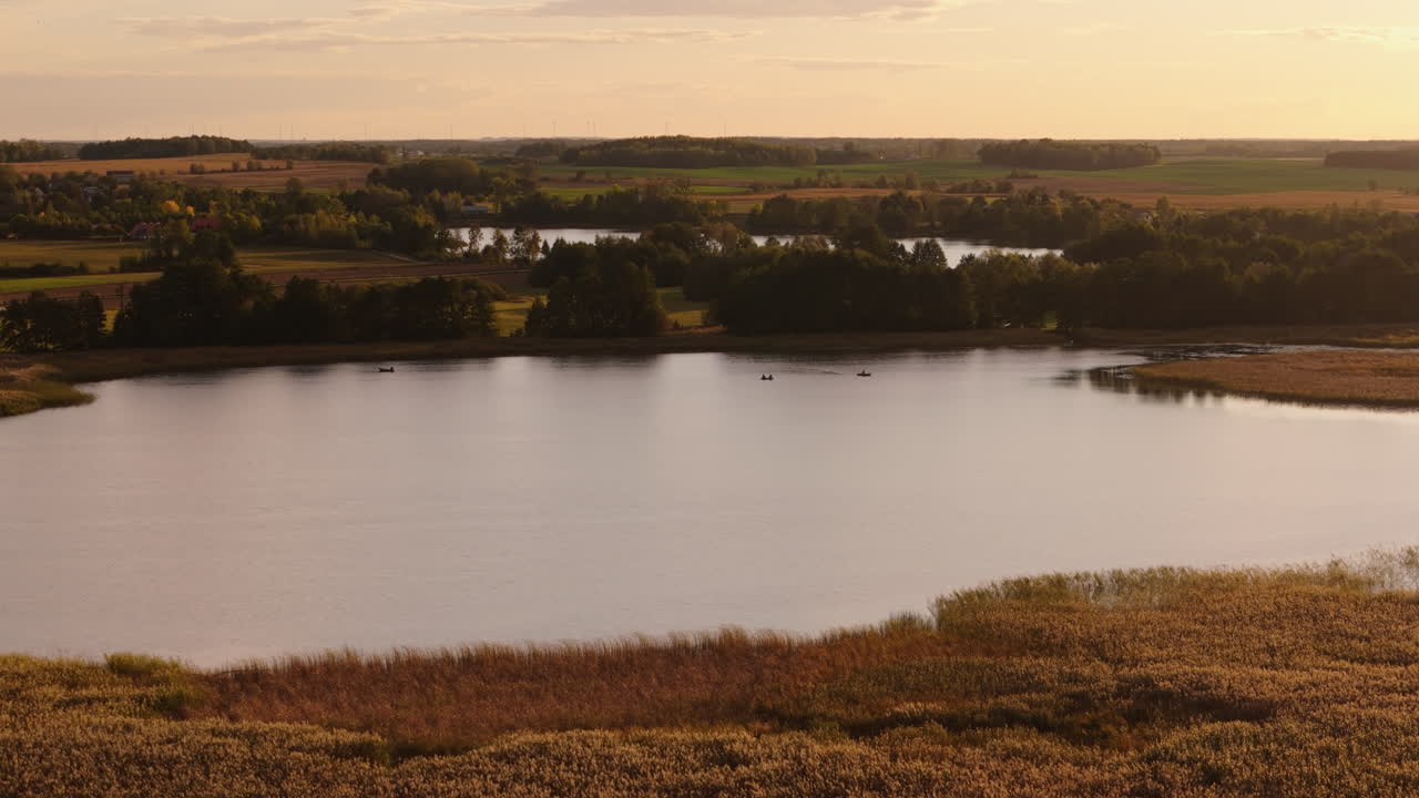 Serene Sunset Lake Landscape with Boats and Rural Scenery