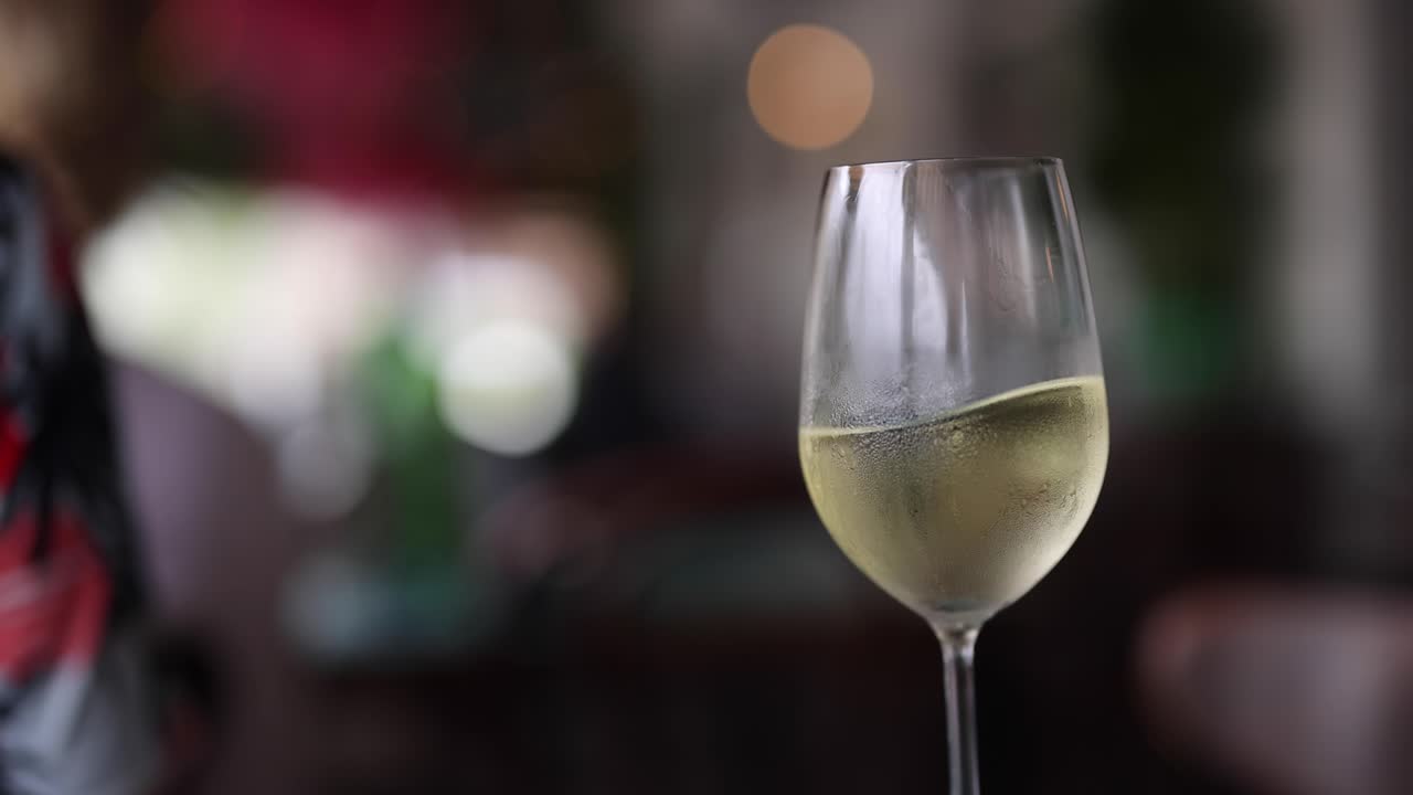 Un bicchiere di vino bianco in rotazione in un ambiente poco illuminato