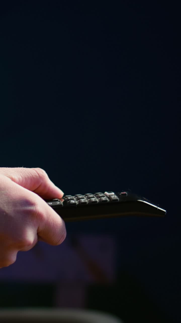 Vertical video Close up of man on couch using remote control