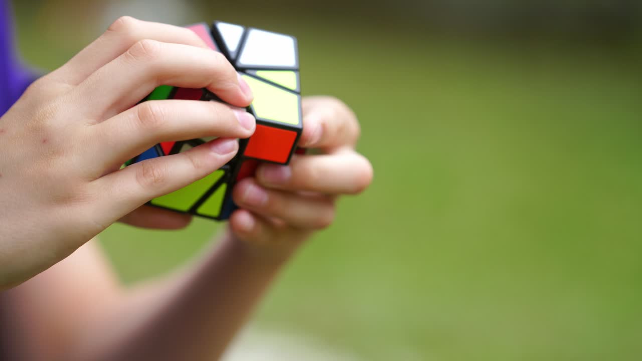 Boy practices with difficult Rubik's Cube. Smart teenager solving puzzle game with new Rubik's cube. Concept of problem solving, solution, focus and goal.