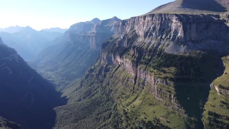 smooth aerial footage of a huge and green chain of mountains at sunrise