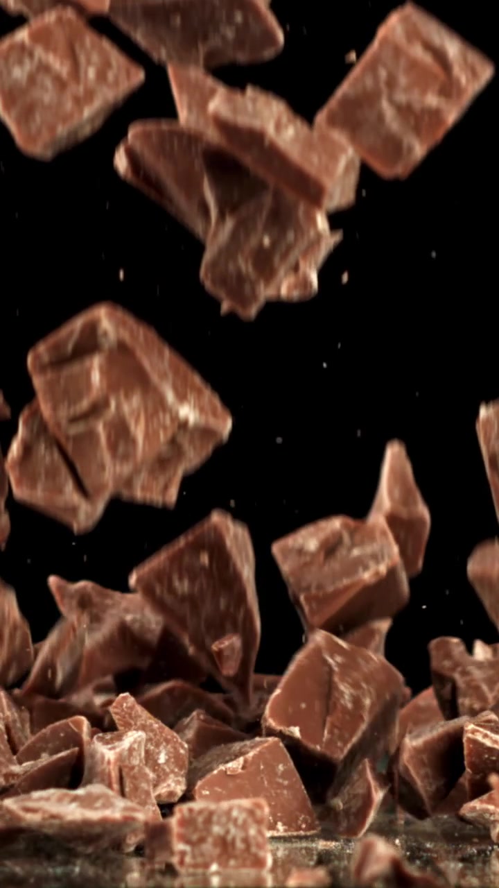 Pezzi di cioccolato che cadono al rallentatore su sfondo nero