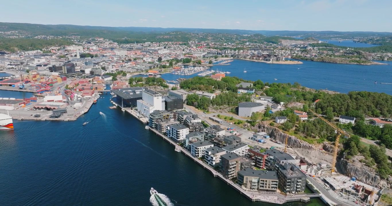 Vista aerea del porto di Kristiansand, Norvegia, con imbarcazioni che mostrano attività marittima e acqua turchese.