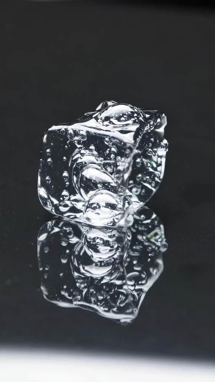 Close-up video concept of a melting ice cube on a reflective surface