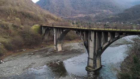 산 계곡 에 있는 강 을 가로지르는 오래된 콘크리트 아치 다리