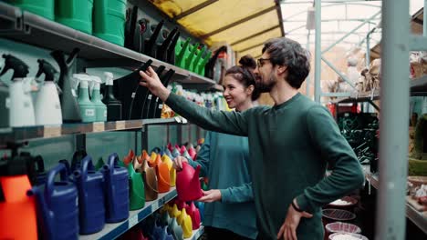 retrato de una pareja joven positiva en la tienda de jardinería, eligiendo un bote de riego