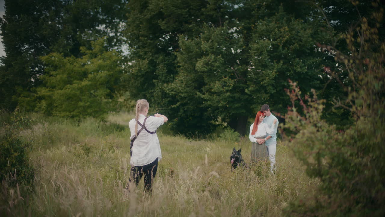 Couple posing with dog in field with photographer