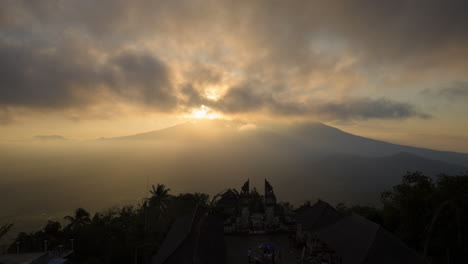 Monte-Agung-Volcán-Durante-La-Hora-Dorada-Puesta-De-Sol-Rayos-De-Sol-Con-Espectacular-Movimiento-De-Nubes,-Puerta-Del-Cielo-Silueta-En-Primer-Plano