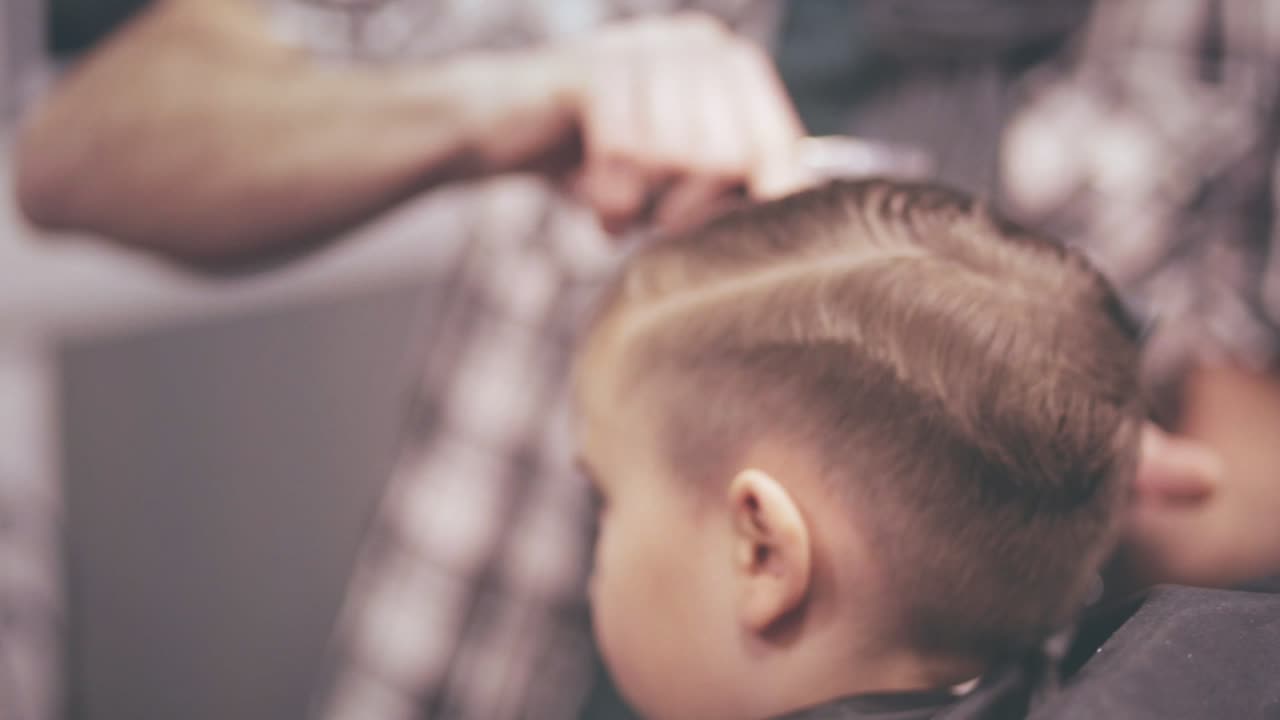 Acconciatura per bambini. Taglio di capelli per bambini. Stilista che pettina i capelli di un bambino. Taglio di capelli bambino.