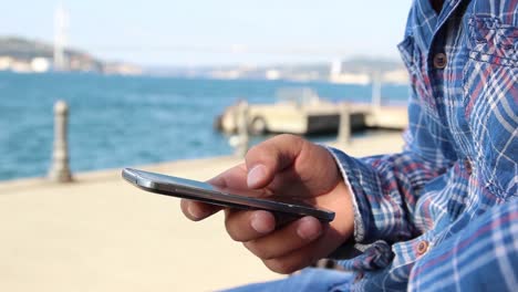 close up shot of man's hands with mobile phone on background sea view 1