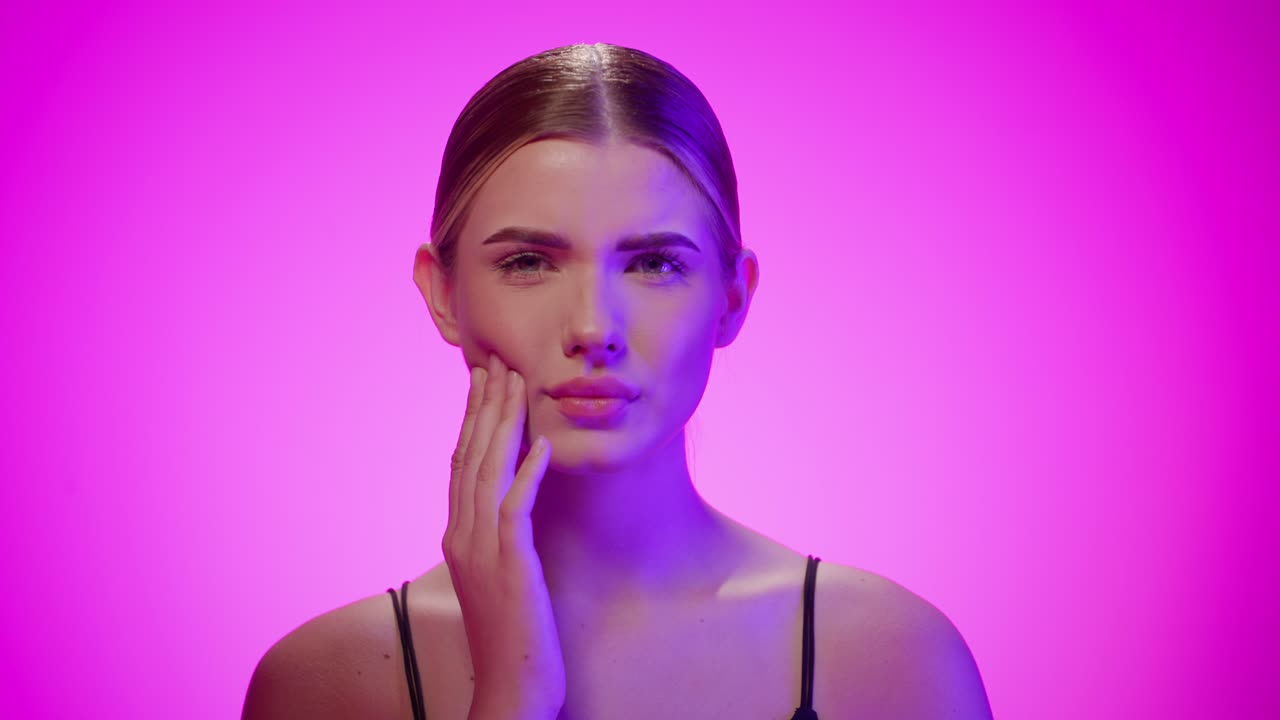 la dama descarada gira los ojos y se frota la mejilla, sin parecer impresionada, toma de estudio rosada