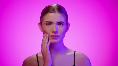 sassy lady rolls eyes and rubs cheek, looking unimpressed, pink studio shot