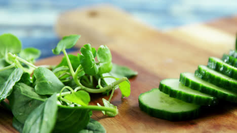 fresh herbs and sliced cucumber on chopping board