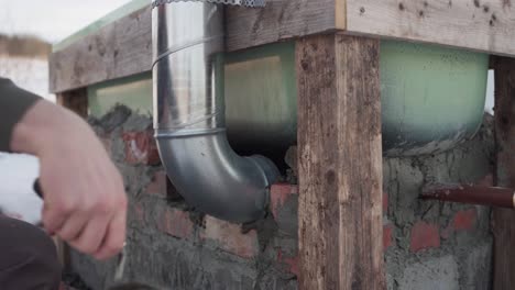 el hombre está aplicando cemento para asegurar los ladrillos alrededor de la chimenea situada debajo de la bañera de baño caliente diy - cerca