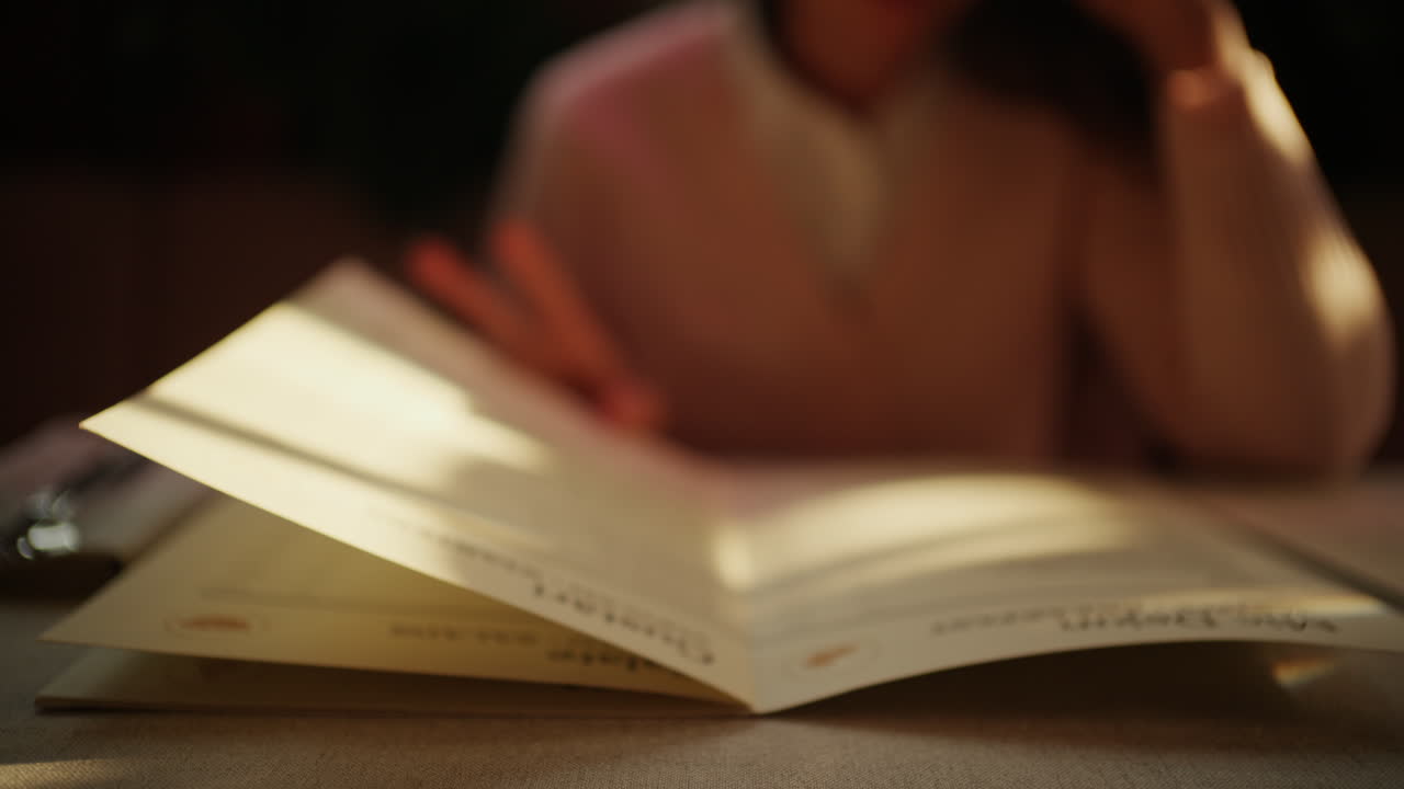 Primo piano di una persona che sfoglia un menu in un ristorante con luce calda.
