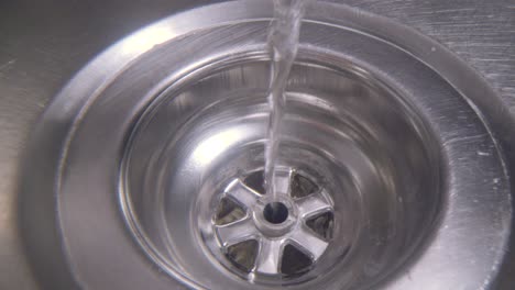 water vortex shot underwater extreme macro close up of a laundry sink plug hole as water empties with a thin jumpy vortex that forms above the lens