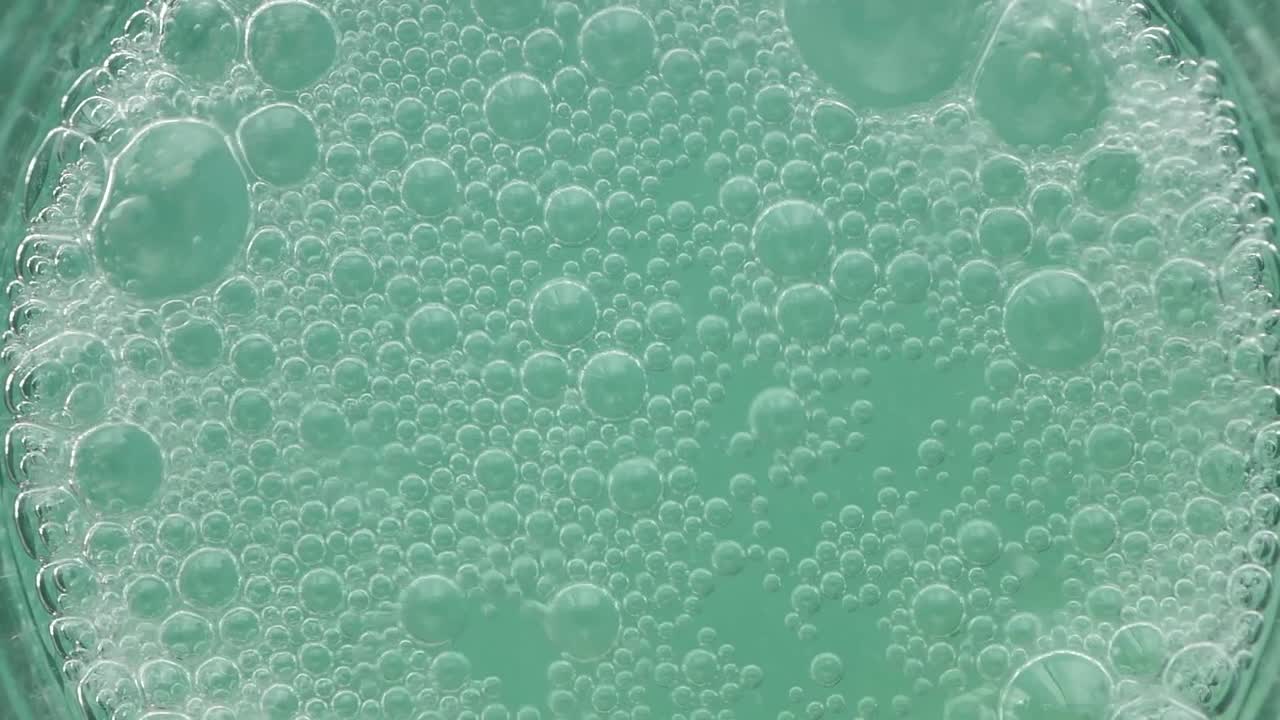 Vista astratta di bolle verdi che scoppiano su una superficie liquida