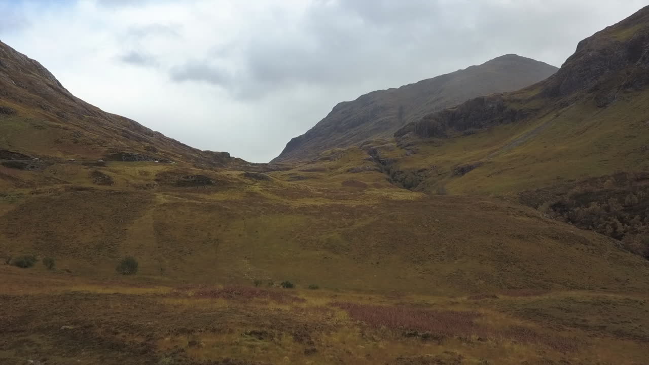 Volo aereo a bassa quota attraverso praterie montane in una valle delle Highland scozzesi