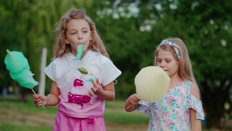 kids having fun in park. cute girls eating cotton candy in park