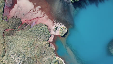 top and rotating aerial view over river carrying a large concentration of glacial silt in its waters, mixing with lake water forming picturesque effect, untouched nature concept