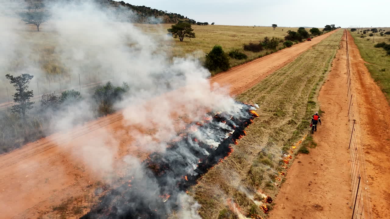 Aerial flyover tracks firefighter creating fire line in wildfire protection zone