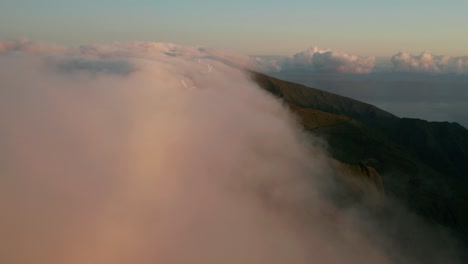 bajada aérea en niebla que fluye sobre montañas con molinos de viento en madeira