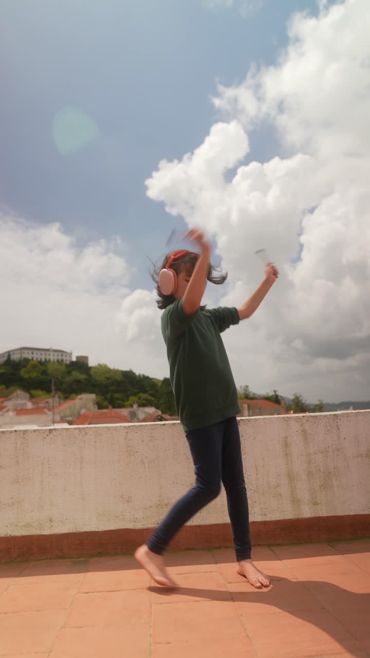 Child Dancing with Drumsticks on a Rooftop