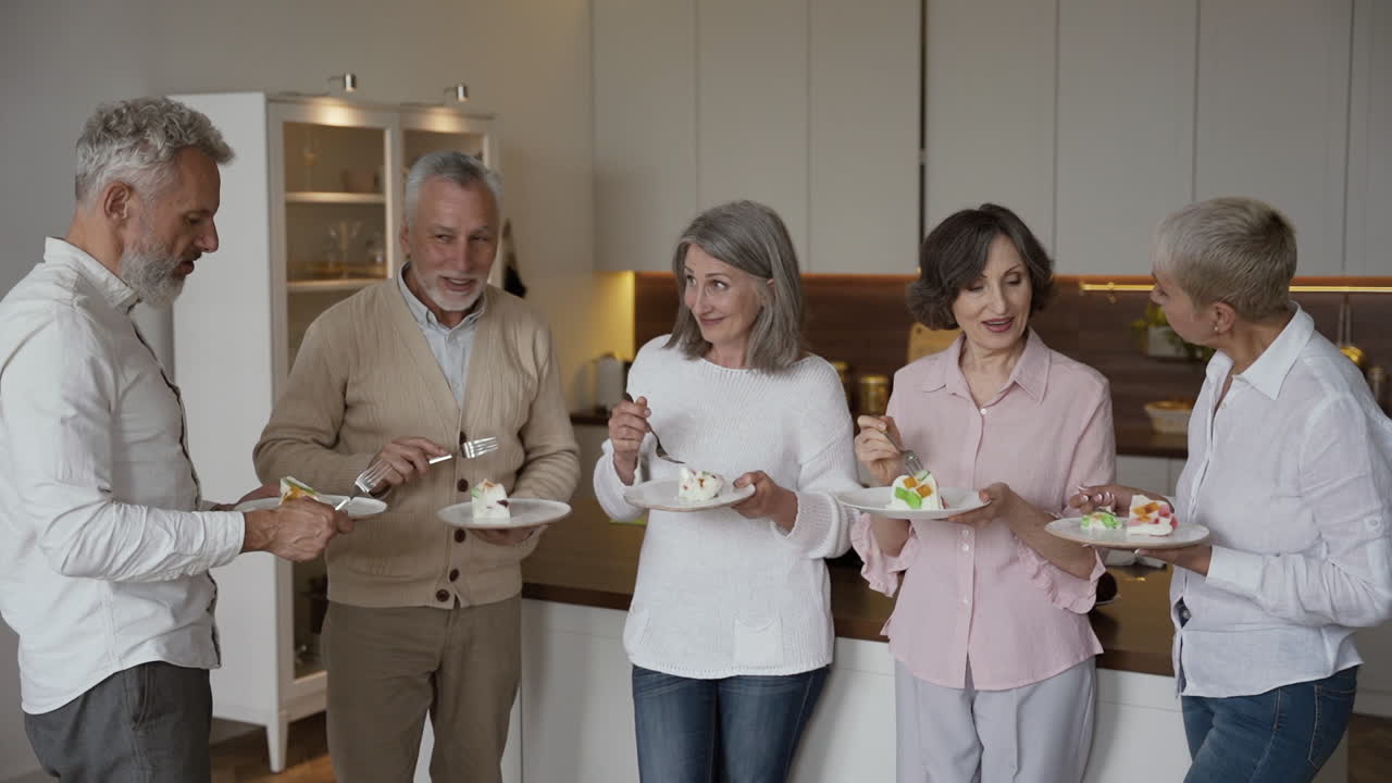 현대적인 스타일의 주방에 서서 맛있는 디저트를 먹고 수다를 떨고 있는 명랑한 선배들