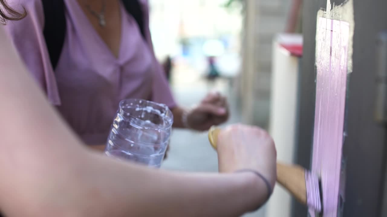 느린 동작으로 브러시로 포스터에 액체 접착제를 바르고 있습니다.